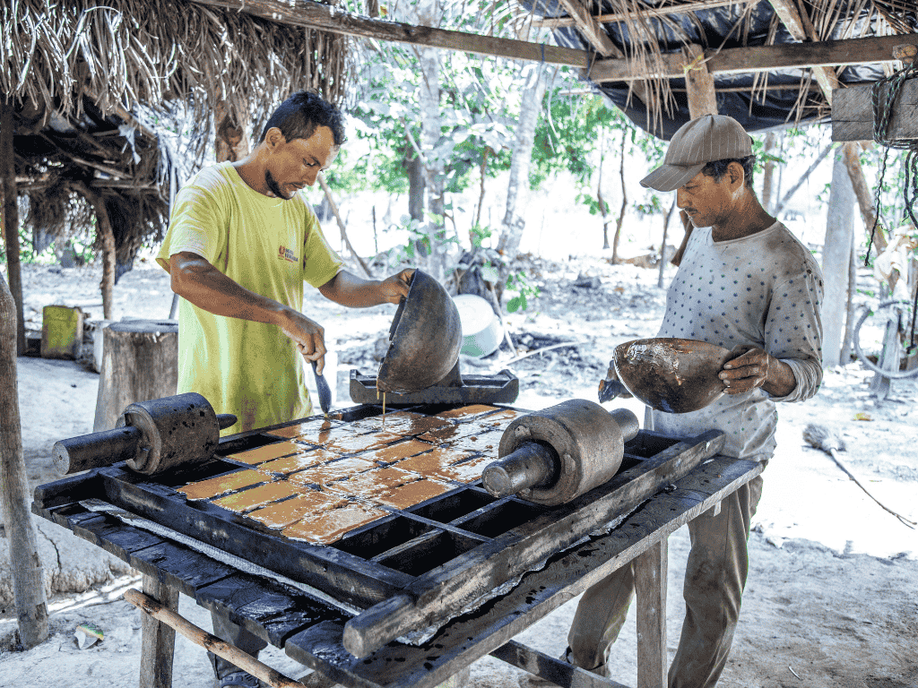 En la imagen se ven dos trabajadores preparando panela