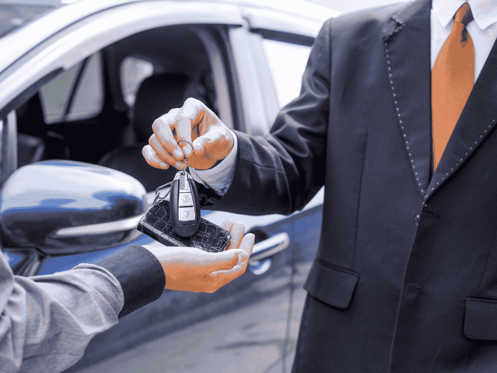 En la imagen se ve a una persona comprando un vehículo y la otra persona le entrega las llaves.